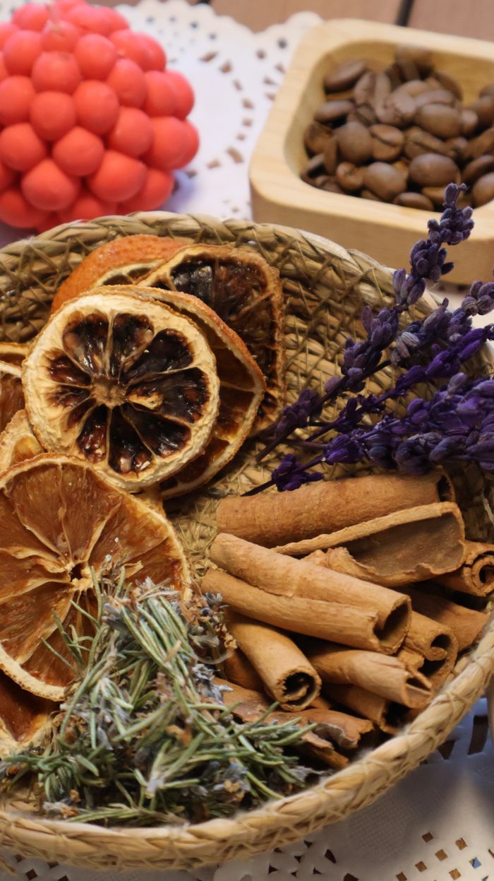 A woven basket filled with dried fruits, cinnamon sticks, lavender, and botanicals for aromatherapy.