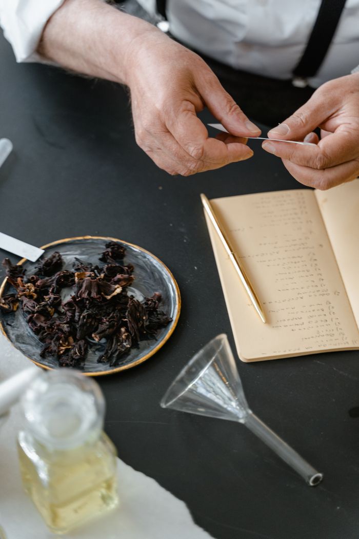 Home Close-up of hands making herbal mix with notes, ideal for aromatherapy.