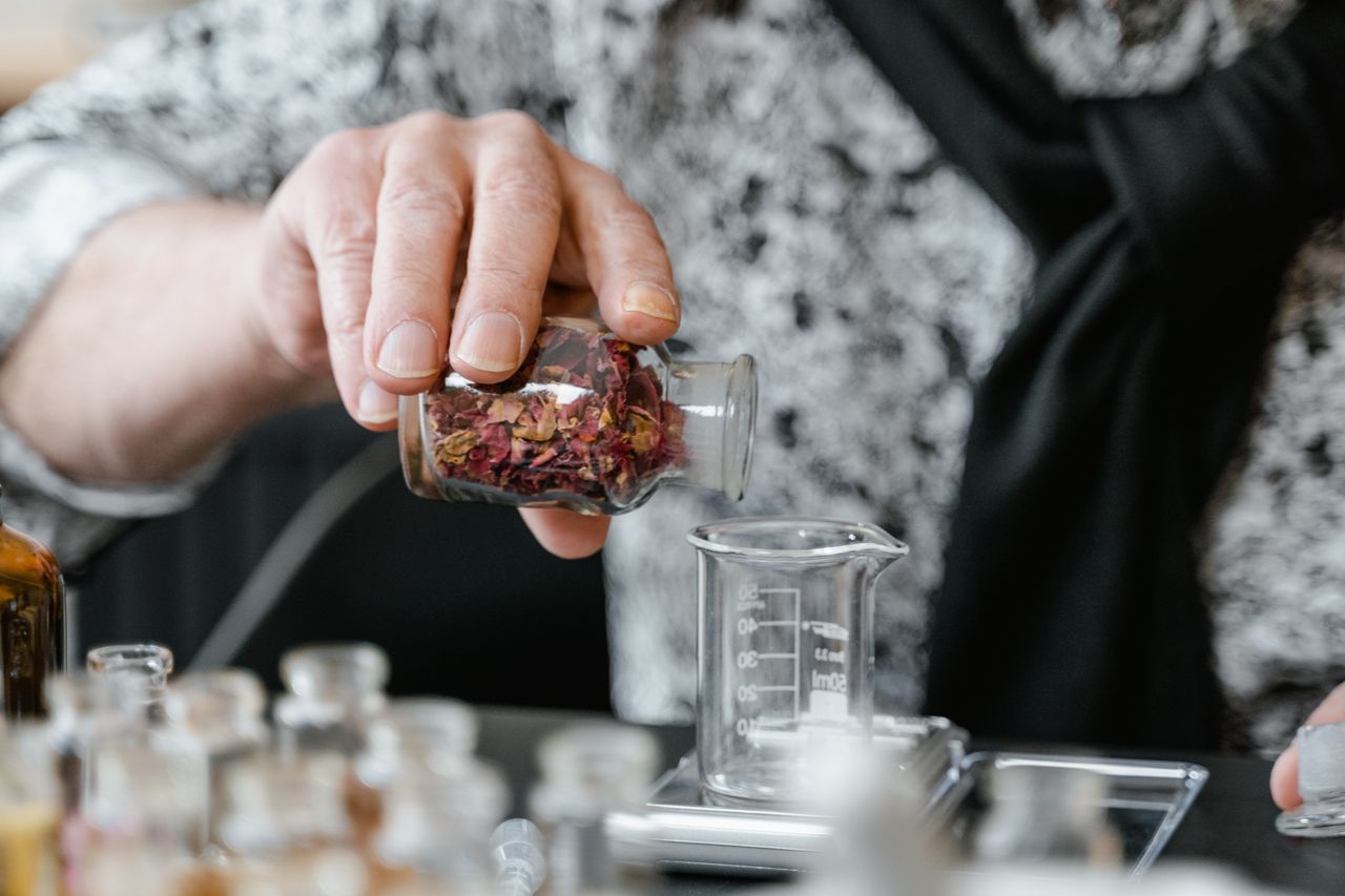 Close-up of a person preparing an herbal infusion with dried leaves in a laboratory setting.